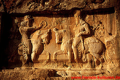 Bishapur - Investiturszene. Bahram I. (rechts) erhält vom Gott Ahura Mazda, der auf den König zureitet, den Ring der Macht, den er entgegennimmt. Die liegende Figur unterhalb des Königs wurde später hinzugefügt. Um wen es sich handelt ist unbekannt.